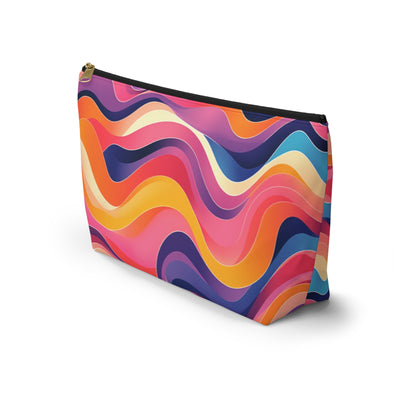 A zippered cosmetic travel bag with a bold, wavy pattern in vibrant colors—pink, orange, yellow, coral, purple, and navy blue. This T-bottom pouch stands upright on a white background, showcasing its colorful, abstract design.