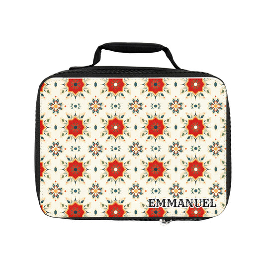 A rectangular, African-inspired lunch tote with a black handle and edges features a repeating pattern of red, orange, and blue kaleidoscopic star shapes on cream. The personalized lunch bag displays the name EMMANUEL in bold black letters at the bottom right corner.