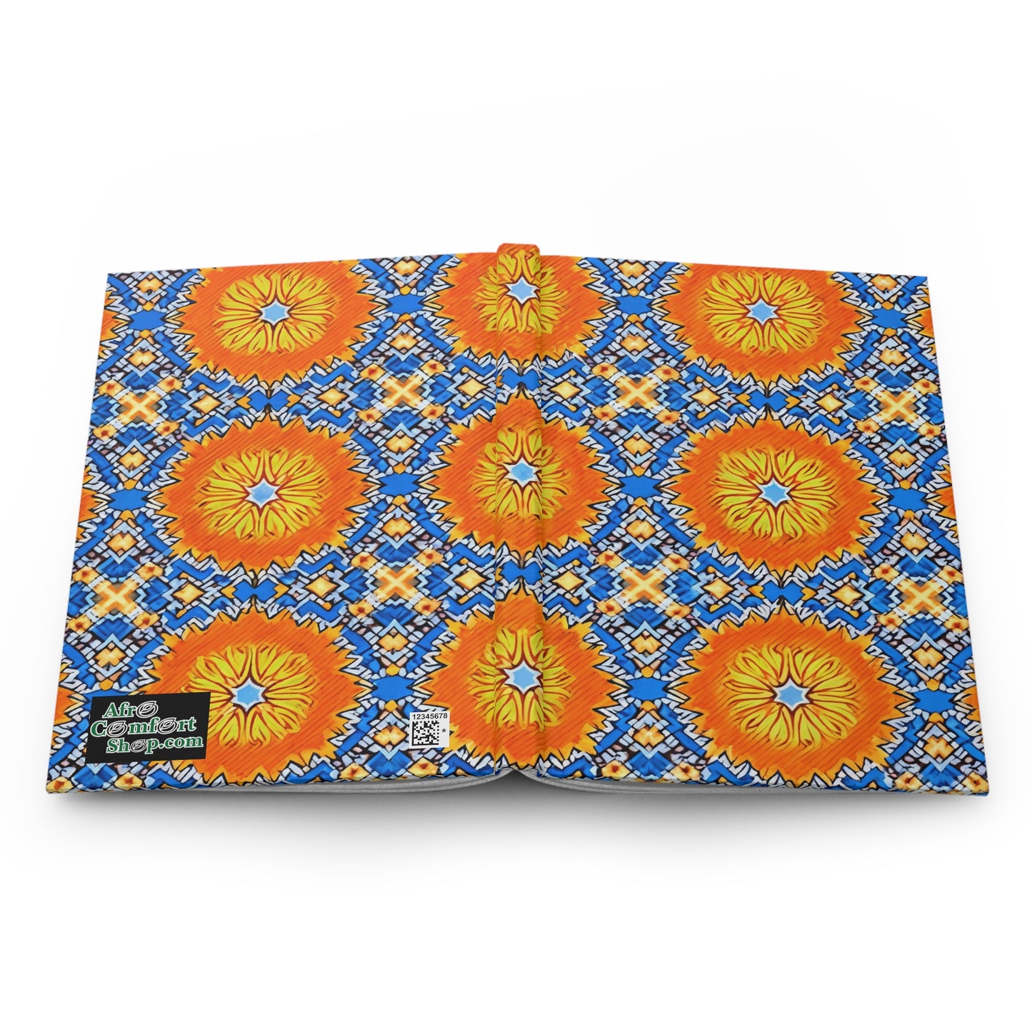 Open book displaying a vibrant pattern of orange and yellow lion faces with blue and yellow sunburst designs on a white background. The back cover features a green “Afro Comix Print” logo and QR code, perfect for an African-inspired journal.