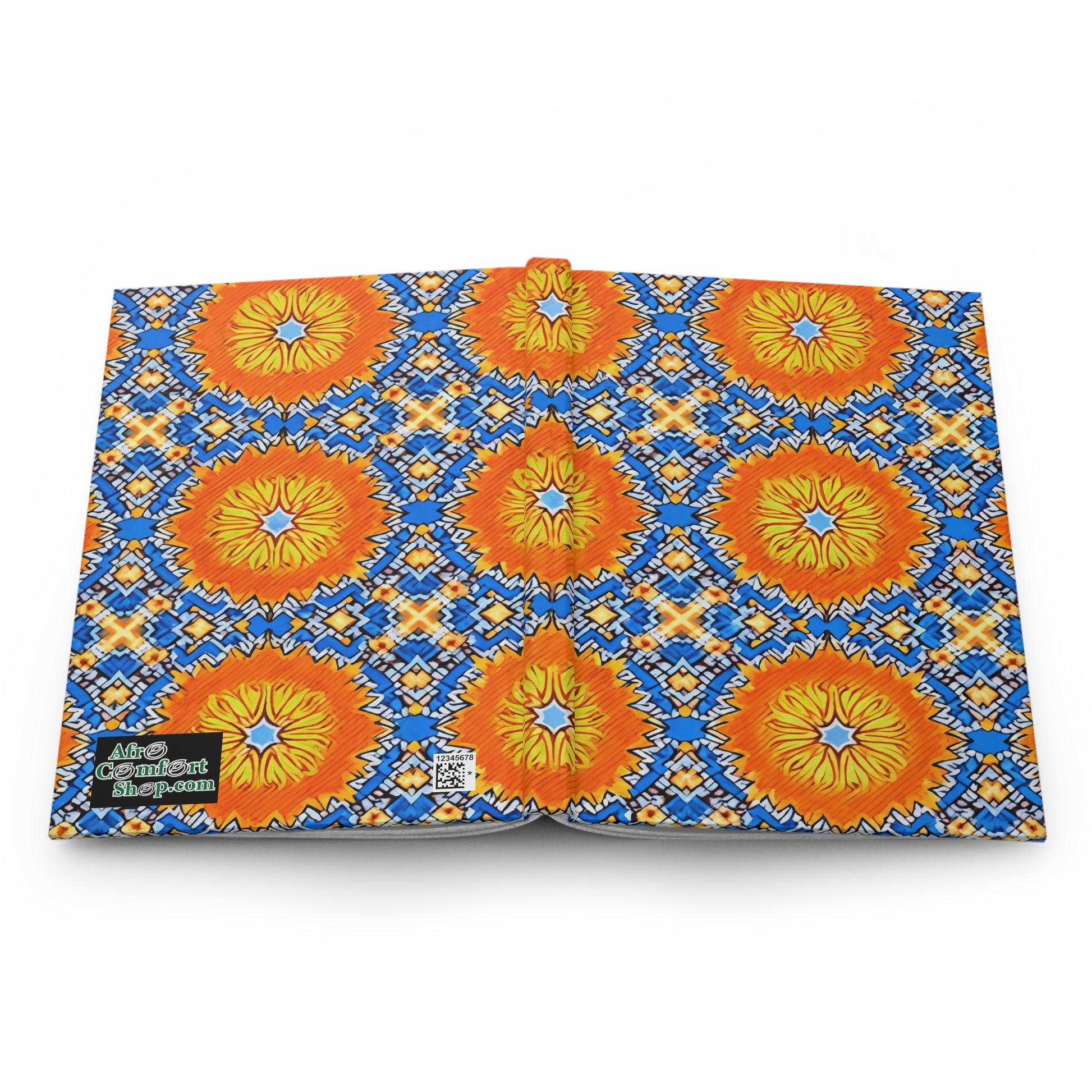 Open book displaying a vibrant pattern of orange and yellow lion faces with blue and yellow sunburst designs on a white background. The back cover features a green “Afro Comix Print” logo and QR code, perfect for an African-inspired journal.