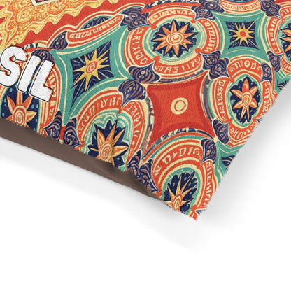 A colorful fabric with intricate, circular mandala patterns in orange, blue, green, and cream covers a cozy dog bed. The fabric features partial bold white text outlined in black on the left that reads SIL, while the edge is slightly frayed.