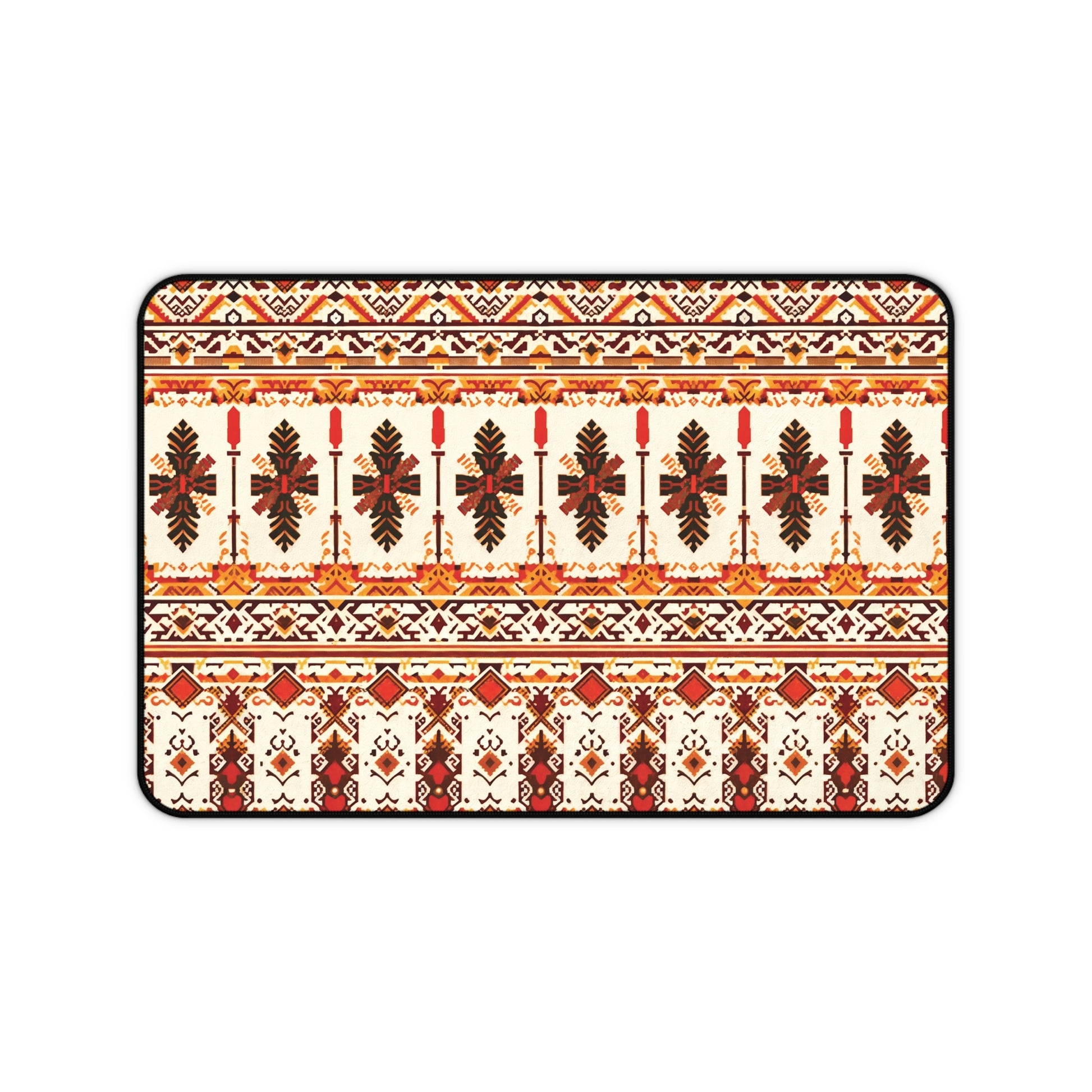 A rectangular neoprene desk mat features a symmetrical, intricate folk-inspired pattern in red, orange, brown, and yellow on a cream background, with repeating rows of stylized leaves and geometric shapes, bordered by a thin black outline.
