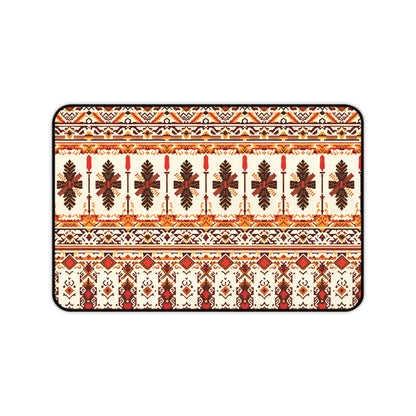 A rectangular neoprene desk mat features a symmetrical, intricate folk-inspired pattern in red, orange, brown, and yellow on a cream background, with repeating rows of stylized leaves and geometric shapes, bordered by a thin black outline.