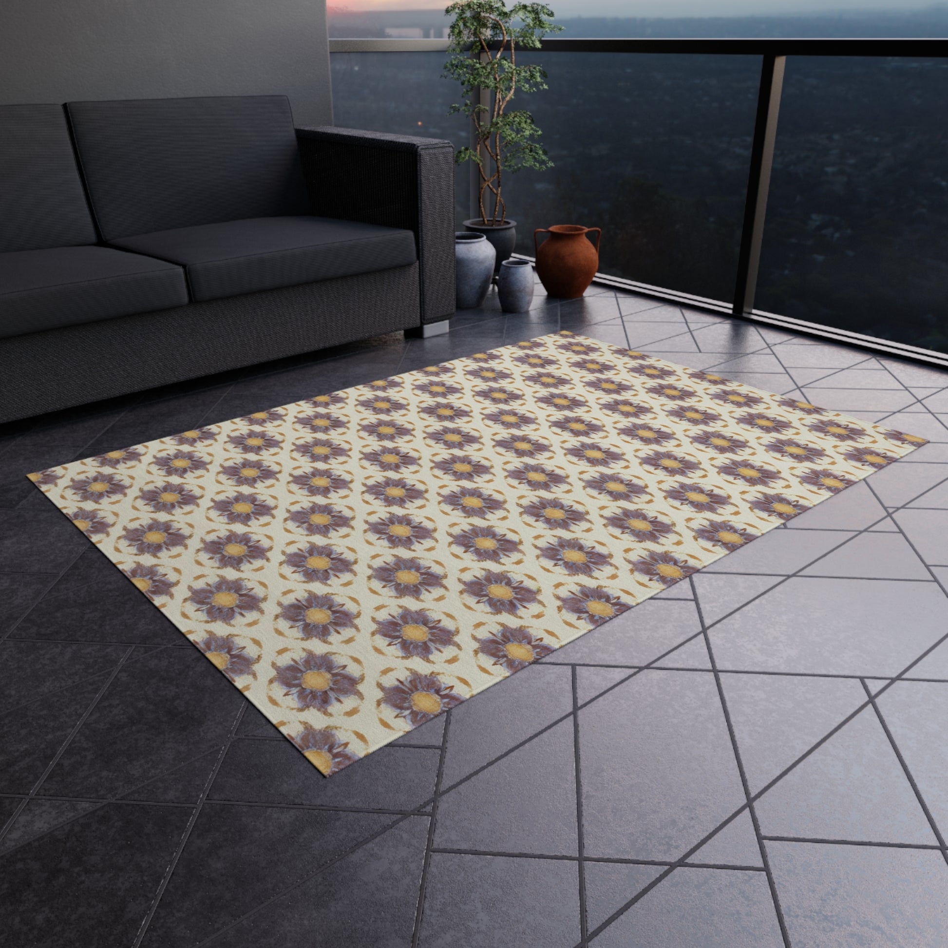 An African-inspired patterned rug with yellow and purple flower motifs lies on a dark-tiled balcony floor. A dark gray sofa, potted plant, and clay pots are nearby, with a hazy cityscape visible beyond the glass balcony railing.