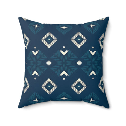 A square decorative pillow with a dark blue background features a geometric pattern of white and teal diamonds, stylized star shapes, and chevrons in a symmetrical design. This vibrant pillow adds bold style to any home decor with its smooth texture and slightly rounded corners.