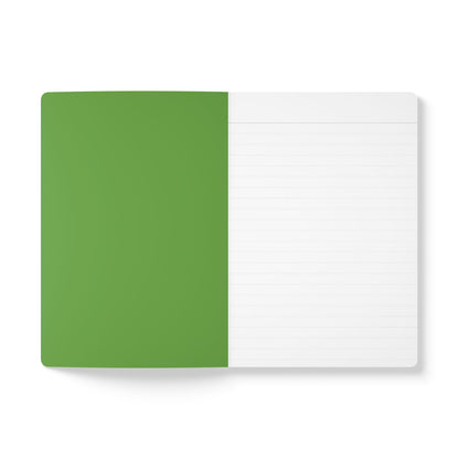 An open creative journal with a green left page and a white lined right page, shown from above on a white background. The left side is solid green, while the right features faint grey lines—perfect for daily journaling.