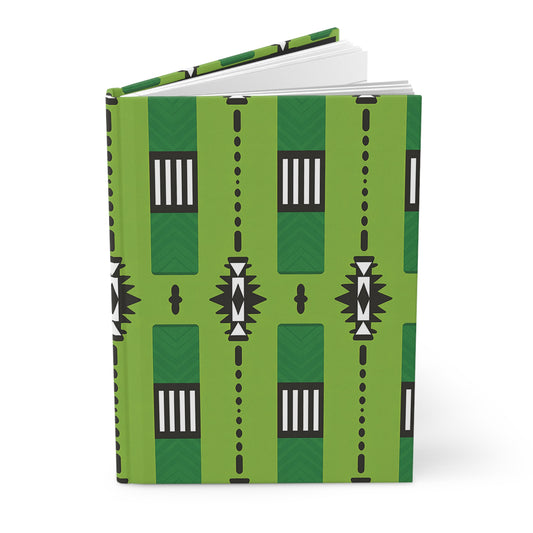 A hardcover journal with a green cover featuring a geometric black, white, and dark green pattern of rectangles, dots, and triangular shapes in vertical rows; this African-inspired journal is partially open, revealing crisp white pages.