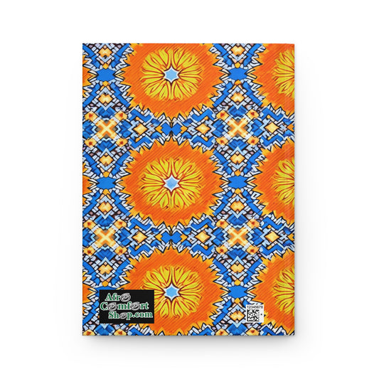 A rectangular, African-inspired hardcover journal with a vibrant cover of orange and yellow sunbursts on a blue and white geometric background. A black label at the bottom left reads AfroComiSart shop.com with a QR code beside it.