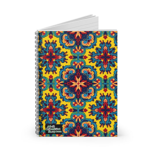 A premium writing journal with a vibrant cover featuring an intricate, symmetrical pattern in red, blue, green, and orange on a yellow background. The African-inspired spiral notebook has a small Artsy Gradient Shop.com label at the bottom left corner.