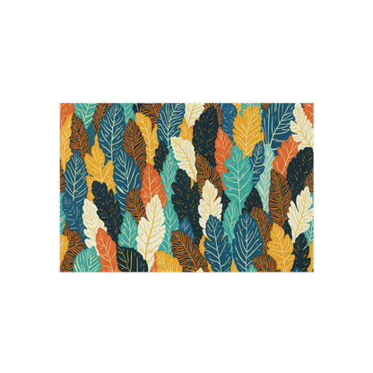 Colorful, overlapping leaves in shades of teal, yellow, orange, cream, and dark blue fill the rectangular image. Each leaf has visible veins in a contrasting color, creating a bold, vibrant African-inspired botanical pattern on a white background.