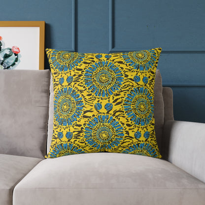 A vibrant accent pillow with a yellow cover features blue and green circular mandala patterns. Placed on a light gray sofa against a blue paneled wall, this African-inspired pillow adds colorful home decor flair beside framed cactus artwork.