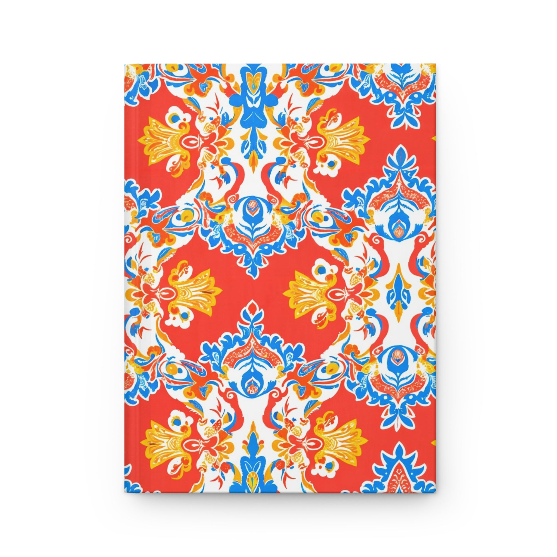 A hardcover journal with a vibrant, symmetrical pattern in blue, yellow, and white on a bright red background. This African-inspired notebook features ornate floral and leaf motifs for an elegant, decorative look. The journal is shown closed on a white surface.