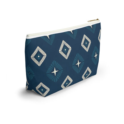 A T-bottom pouch with a blue background, featuring African-inspired patterns of diamond shapes and central star motifs in white and light blue. The pouch stands upright, perfect as a cosmetic travel bag, with a white zipper and gold pull against a plain white background.