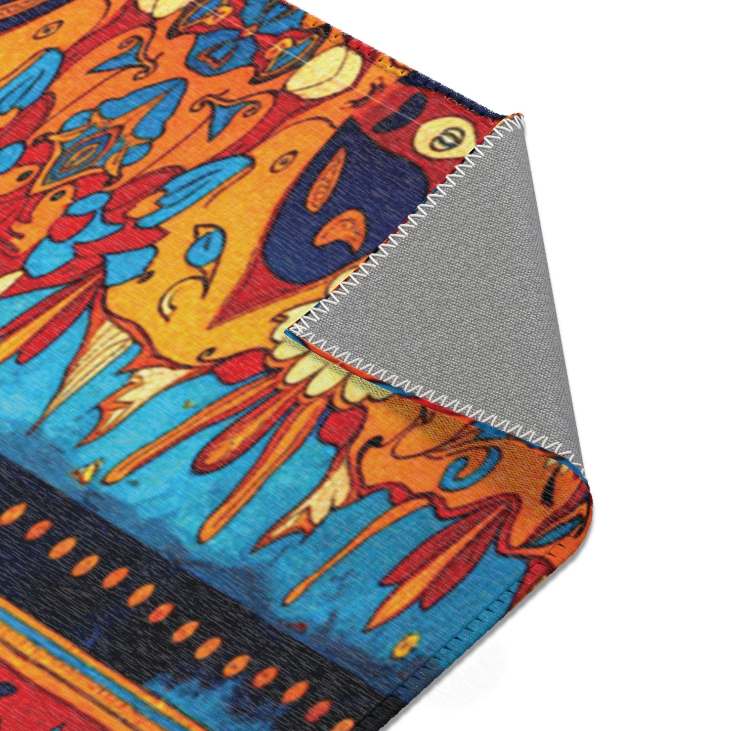A close-up of a stylish, colorful rug inspired by African design rugs displays vivid orange, blue, and red patterns. The corner is folded over, showing a stitched edge and plain gray underside that highlights its durable polyester material.