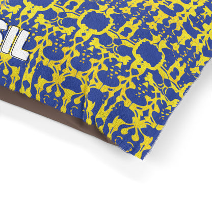 A close-up of a fabric with an African-inspired blue and yellow abstract floral pattern. The edge is frayed, and part of the word SIL in white text with black outline is visible on the left. The background is plain white.