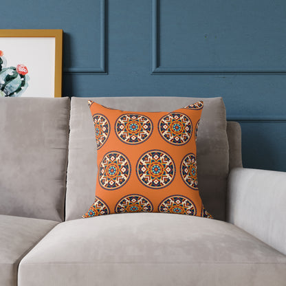 A colorful accent pillow with an orange background and circular, geometric patterns sits on a light gray sofa. Behind it, a blue paneled wall and a framed cactus artwork add to the vibrant home decor of the space.