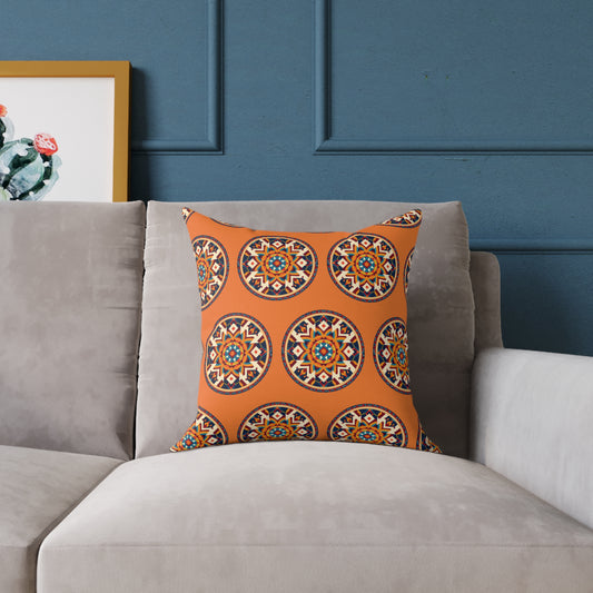 A colorful accent pillow with an orange background and circular, geometric patterns sits on a light gray sofa. Behind it, a blue paneled wall and a framed cactus artwork add to the vibrant home decor of the space.