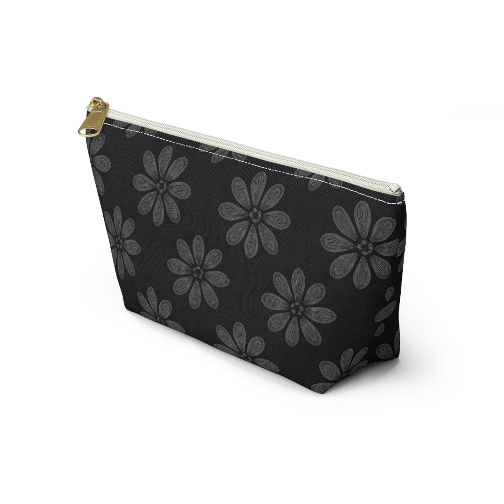 A black cosmetic travel bag with a gold zipper pull, featuring large, light gray, hand-drawn daisy-like flowers reminiscent of African-inspired patterns. This T-bottom pouch stands upright on a white background.