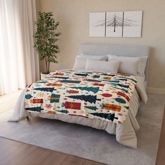 A neatly made bed with a festive, African-inspired blanket featuring Christmas trees, presents, snowflakes, and ornaments in vibrant hues. The bed has gray and white bedding, with a minimalist tree artwork above and a potted plant beside sheer curtains.