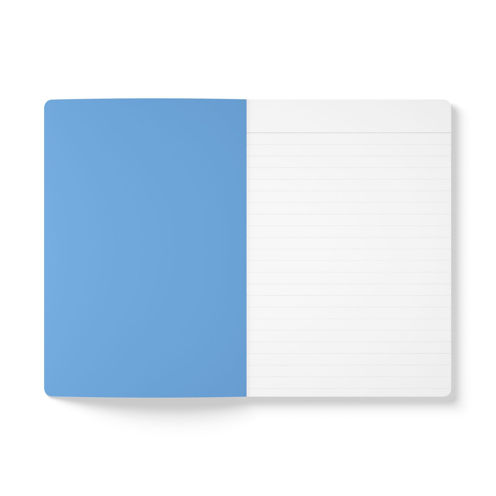 An open creative journal lies flat on a white surface. The left page is solid light blue and blank, while the right page is white with faint gray horizontal lines. The notebook has rounded corners and a minimal, clean design.