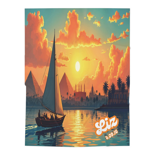 A sailboat with several people glides on a river at sunset, with glowing clouds, pyramids, mosques, palm trees, and distant buildings on the horizon—an enchanting scene perfect for African-inspired decor or a personalized baby blanket.