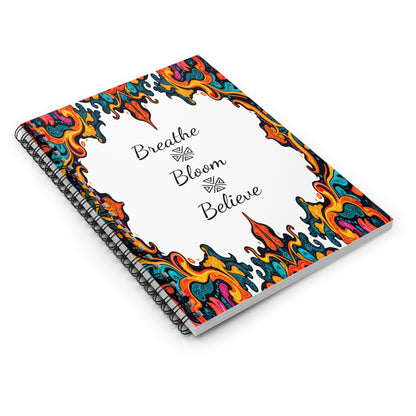 Spiral notebook with a white cover featuring vibrant, multicolored abstract flame designs on the borders. The center displays the words “Breathe Bloom Believe” in elegant black script, inspired by African geometric notebook patterns.