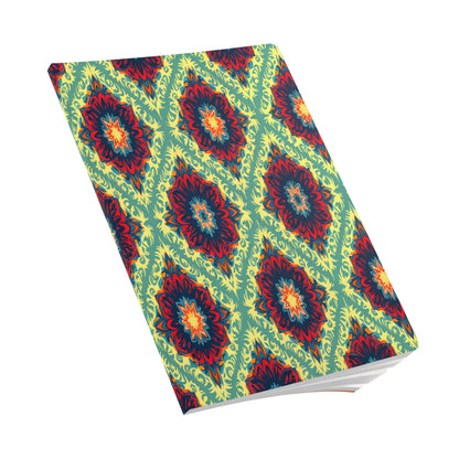 A closed African-inspired journal with a vibrant, geometric pattern in red, yellow, blue, and green. The cover features repeating diamond shapes and floral-like motifs on a light green background. Perfect for daily journaling, it rests at an angle on a white surface.