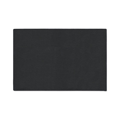 A rectangular, flat black non-slip rug with subtle textured patterns is centered on a white background. The edges are neatly stitched, and its surface appears smooth and even. The mat has no visible designs or logos.