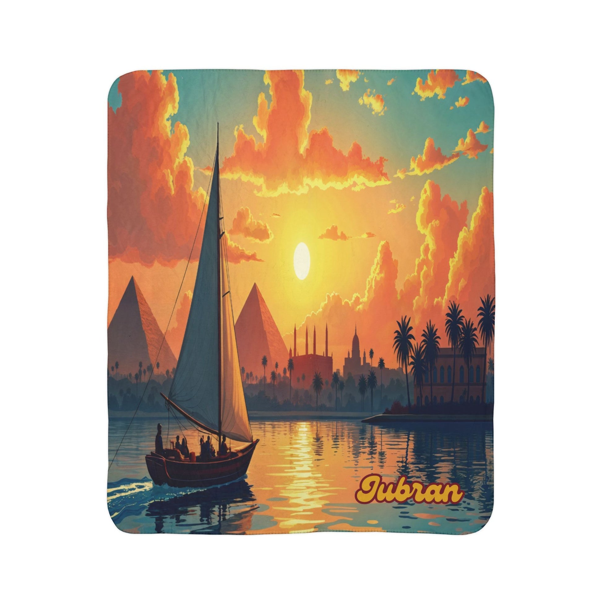 A sailboat with people glides on a river at sunset, passing palm trees and historic buildings. Three pyramids rise in the background, evoking African-inspired fleece blankets and home decor. The word TUBRAN appears in bold script at the lower right.