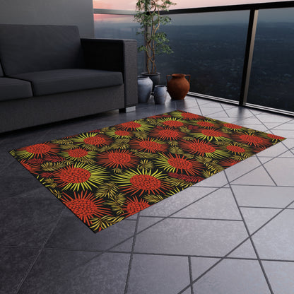 A modern balcony with a gray tiled floor features an African-inspired rectangular rug with a bold floral pattern in red, yellow, and green. A gray sofa, potted plants, and clay vases decorate the space. Cityscape and sunset shine through the glass railing.