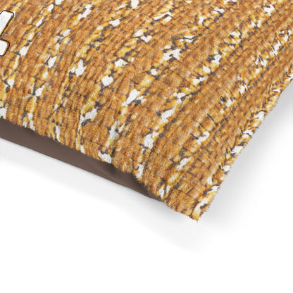 A close-up of a rectangular, stylish pet bed pillow with a textured, woven golden-brown pattern and white highlights on top, plus solid dark brown fabric on the side. The pillow’s corner is visible against a plain white background.