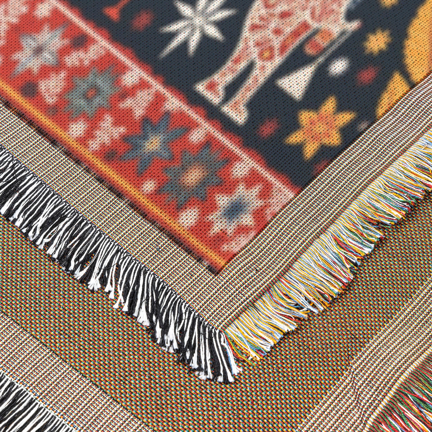 Close-up of a vibrant throw blanket with a cozy weave, featuring a border of red and blue stars, fringed edges in black, white, and multicolored threads, and part of an animal figure on a dark background adorned with yellow and white star patterns.