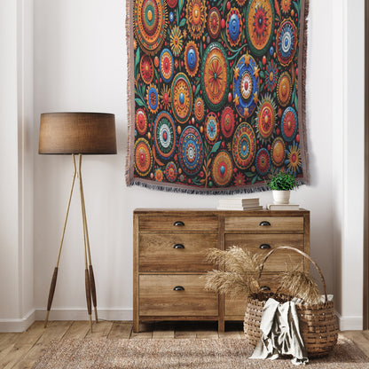 A cozy room features a wooden dresser with a potted plant, a wicker basket of dried grasses, a tripod floor lamp, and a vibrant West African print textile hanging on the wall above the dresser.