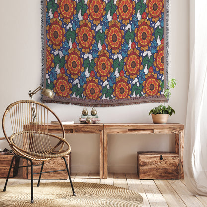 A cozy, African-inspired room with a wicker chair, a rustic wooden bench filled with books and a potted plant, and a colorful floral tapestry on the wall. Sunlight filters through sheer curtains onto wooden floors and two wooden storage boxes under the bench.