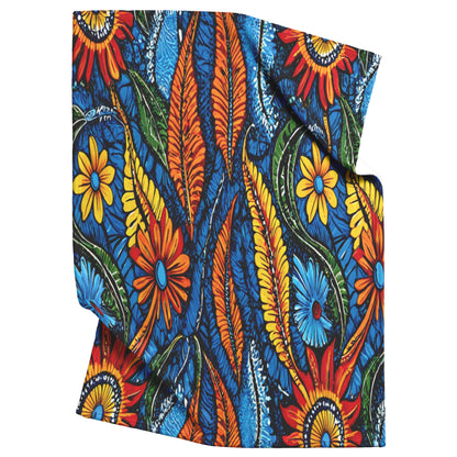A folded cloth with a vibrant, African-inspired pattern of orange, yellow, and red flowers, green and orange leaves, and blue swirls on a bold blue background. The design is colorful and energetic, creating a lively appearance.