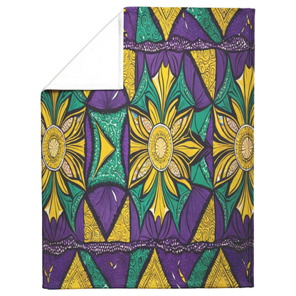 A sherpa-backed fleece blanket featuring a bold geometric pattern in yellow, green, and purple. Large starburst flower motifs, swirling lines, and repeating shapes create a vibrant look. The corner is folded to reveal the soft white underside.
