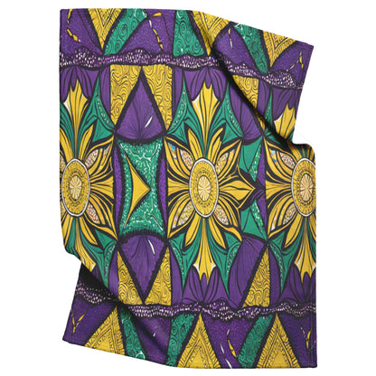 A folded African-inspired fleece blanket with a vibrant geometric and floral pattern in yellow, green, and purple. The design features repeated starburst shapes, swirls, and triangular motifs for a bold, symmetrical look.