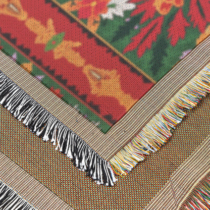 Close-up of an African-inspired woven textile with a colorful floral pattern in red, green, yellow, and white. Two fringed edges cross at an angle—one black and white, the other multicolored—with fabric texture and fibers clearly visible.