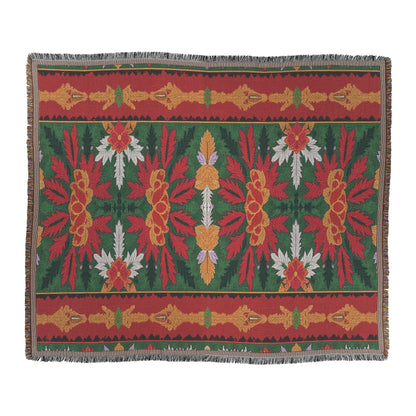 A rectangular woven rug with a fringe border, featuring African-inspired symmetrical red, yellow, green, and white floral and leaf patterns. The design is organized in horizontal bands with central motifs and repeating decorative edge elements.