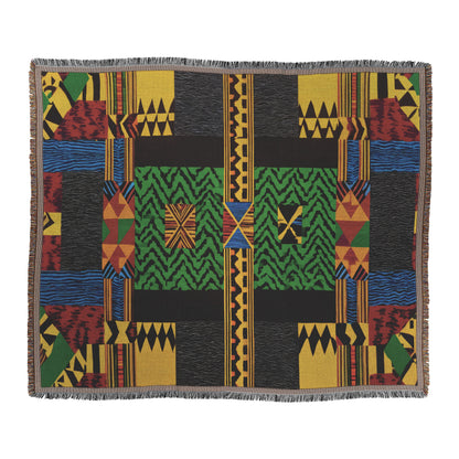 A rectangular cozy woven blanket features geometric patterns in green, red, yellow, blue, and black. The design includes zigzags, stripes, triangles, and rectangles with a symmetrical layout and fringed edges for a bold and intricate look.