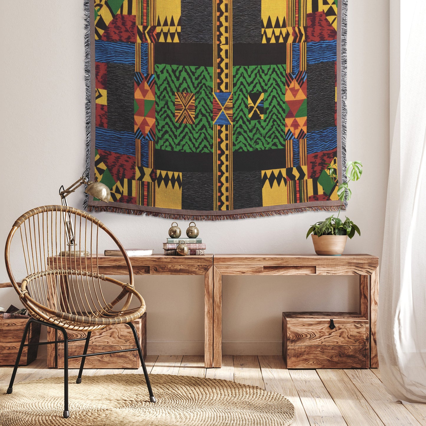 A cozy room features a wooden bench with books, a potted plant, and a round rattan chair draped with a vibrant throw blanket. A colorful West African print tapestry hangs on the wall above, as sunlight filters in through sheer curtains.