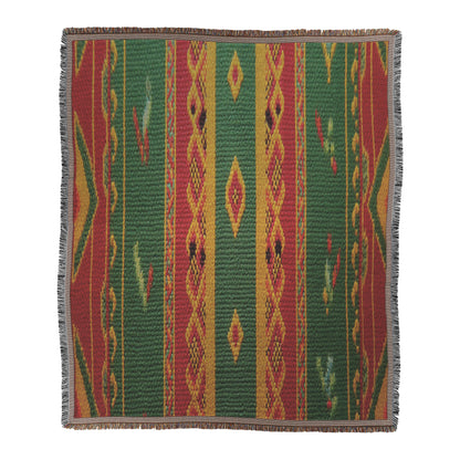 An African-inspired rectangular woven textile featuring vertical stripes in green, red, and yellow with diamond and zigzag geometric patterns. The blanket showcases multicolored designs and a fringed edge in black and white.