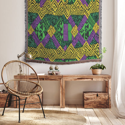 A cozy room with a woven rattan chair on a round rug, next to a wooden bench adorned with books and decor. A vibrant throw blanket adds color, while above, a geometric tapestry in green, yellow, and purple brightens the softly lit space.