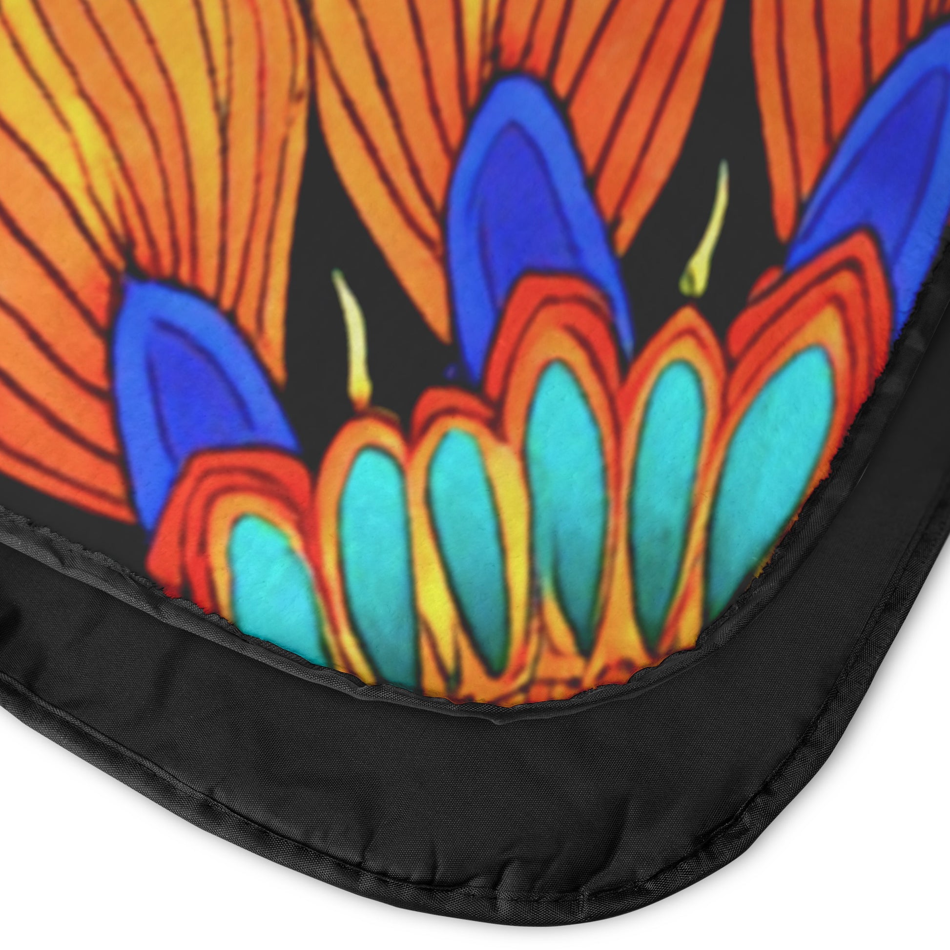 Close-up of a blanket corner featuring a vibrant, abstract floral design in orange, blue, yellow, and teal hues on a black background. A plush fleece top and black fabric binding frame the edge, emphasizing the bright, African-inspired pattern.